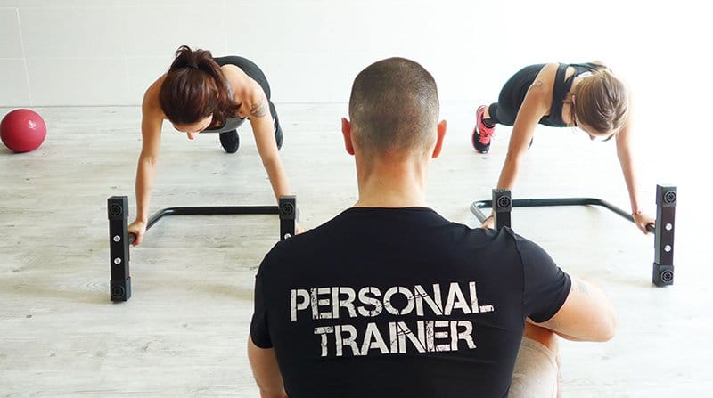 Un coach avec deux femmes qui font du gainage