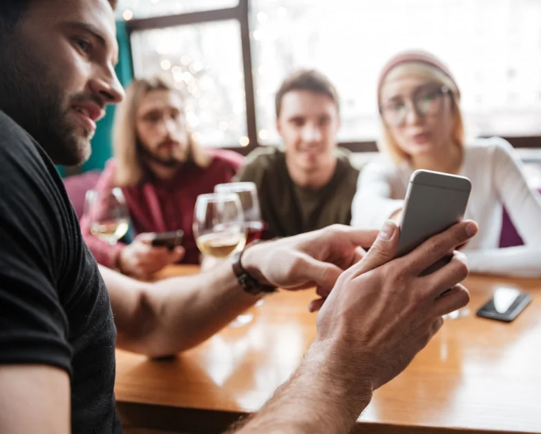 Un homme montre son smartphone à ses 3 amis amis.