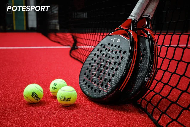 Deux raquettes de padel et trois balles sur un terrain de padel