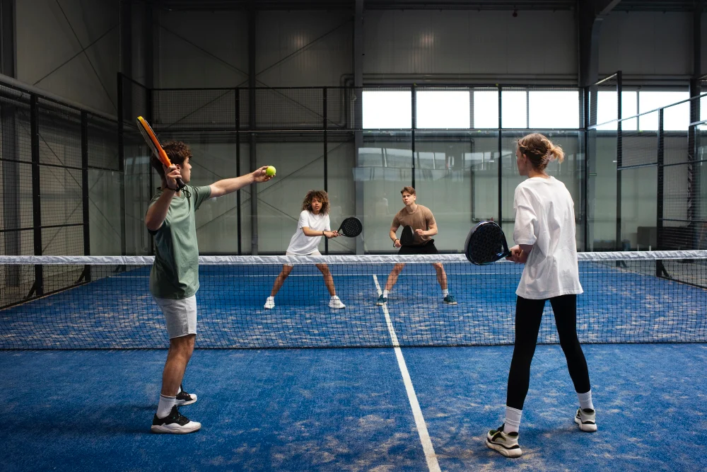 Quatre. Amis font un match de padel sur un terrain indoor.