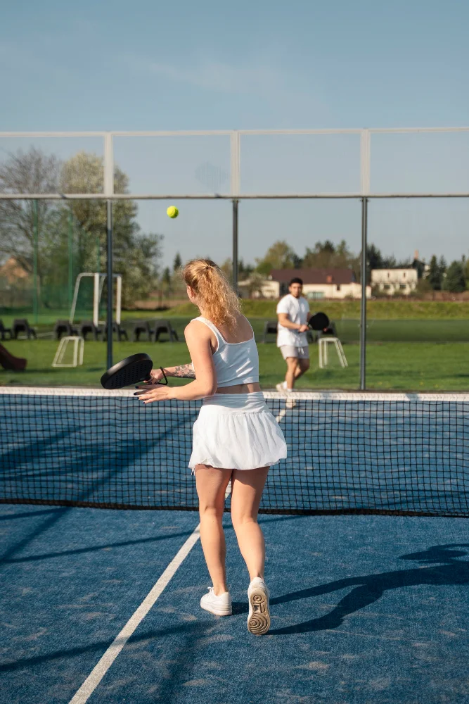 Une jeune femme de dos, renvoie la balle à son adversaire, lors d'un match de padel