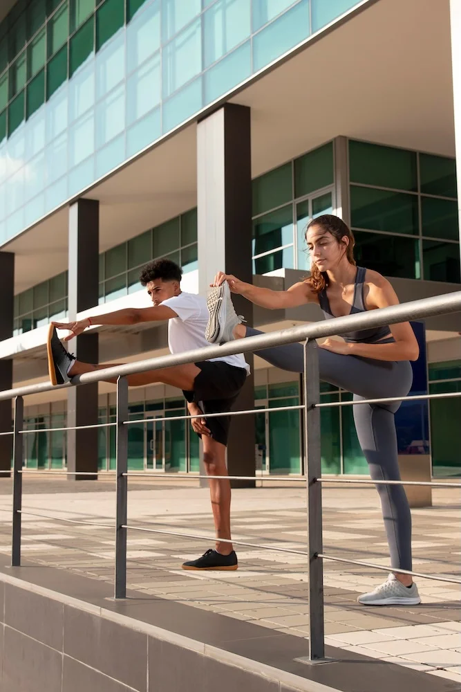Un couple de sportif qui s'étire les muscles des jambes sur une balustrade
