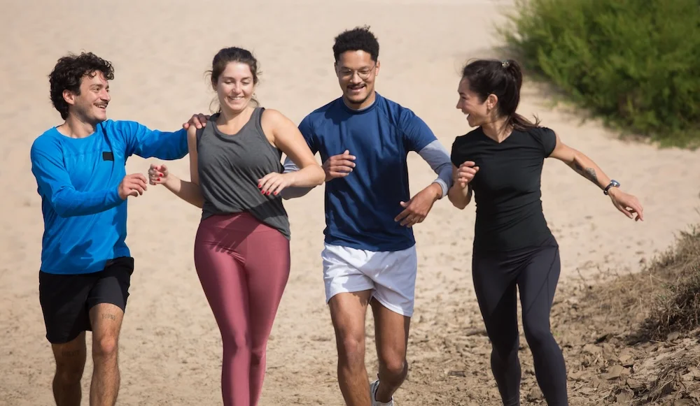 partenaire running Quatre personnes font du running sur la plage.
